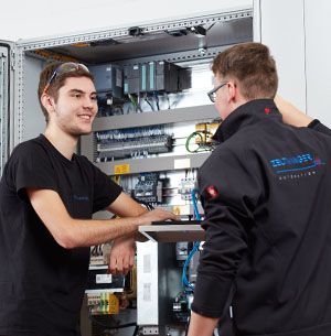 Two trainees in front of a control cabinet
